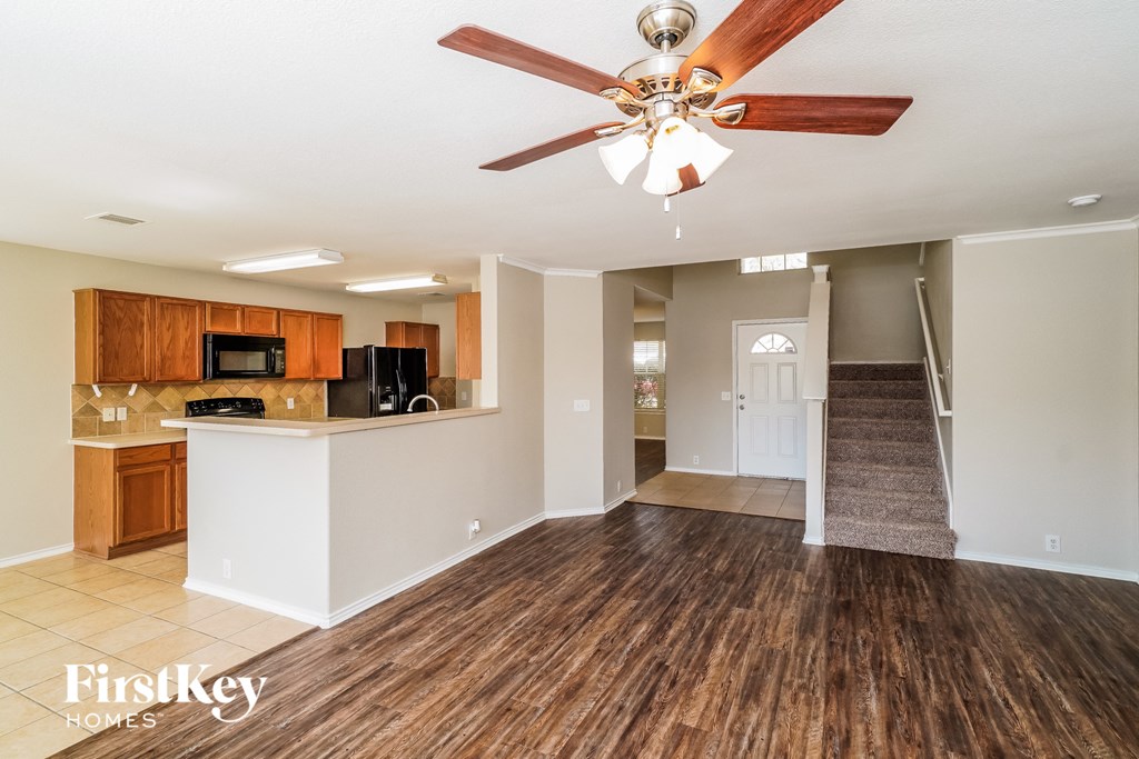 A spacious room with a wood floor and a ceiling fan.