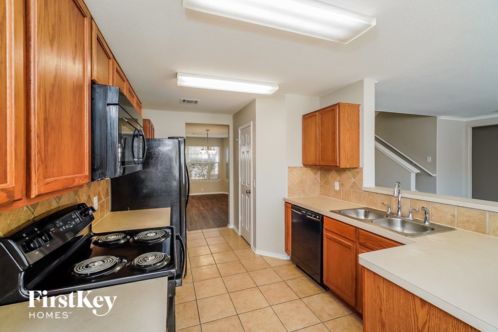 A kitchen with wooden cabinets and a black fridge.