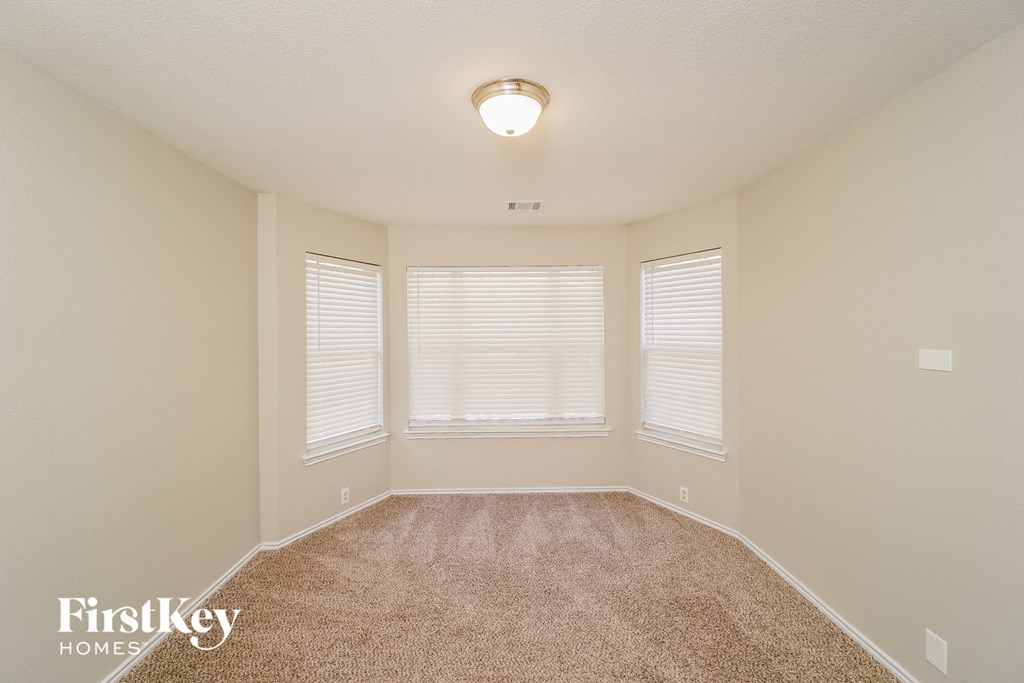 A carpeted room with a window and a light on the ceiling.