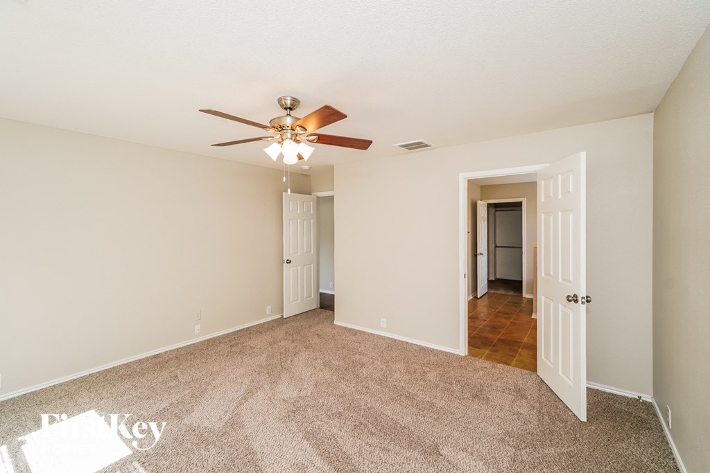 A room with a ceiling fan and carpeted floor.