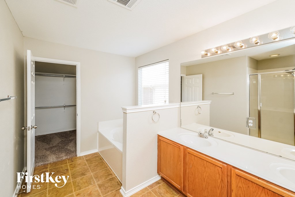 A bathroom with a tub, sink, and mirror.