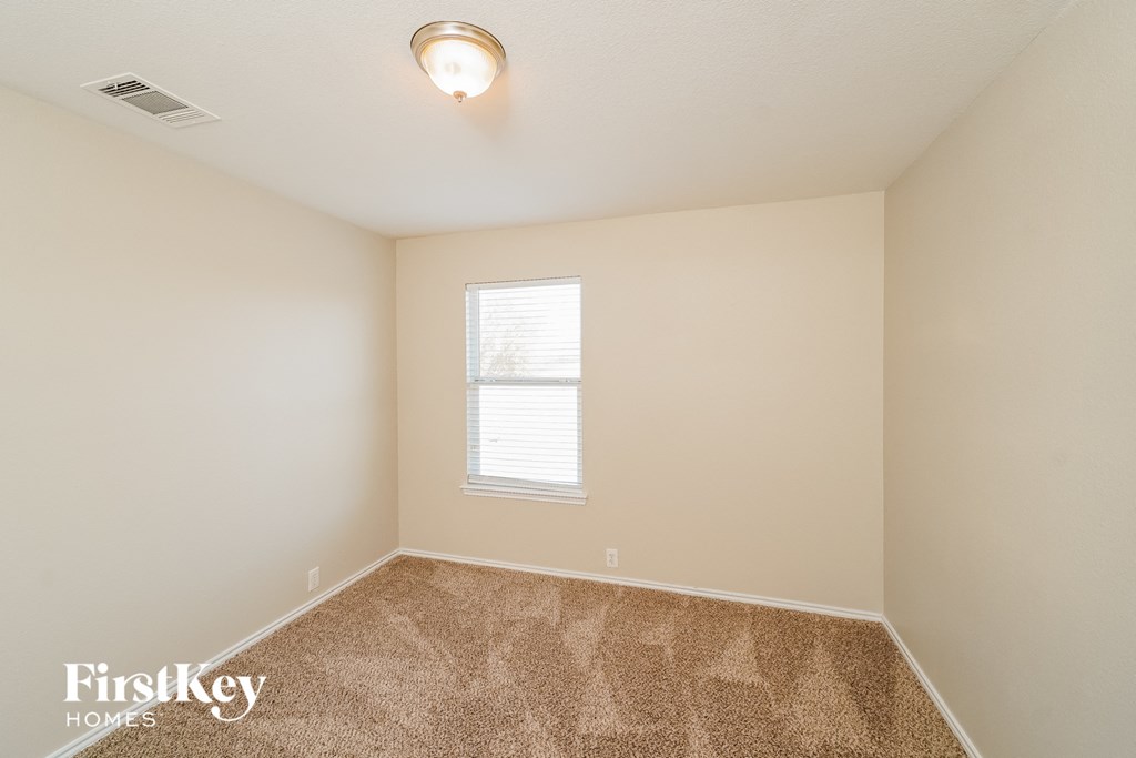 A room with a carpeted floor and a window with blinds.