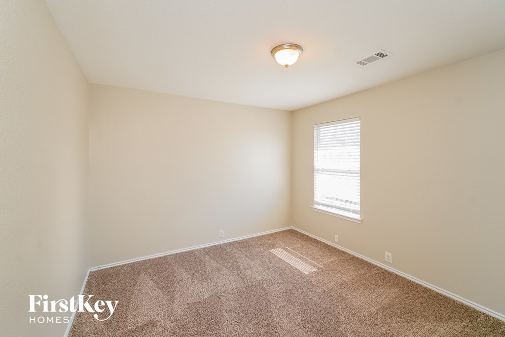A room with a carpeted floor and a window with blinds.