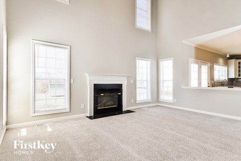 an empty living room with a fireplace and windows