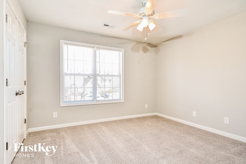 a bedroom with carpet and a ceiling fan and a window