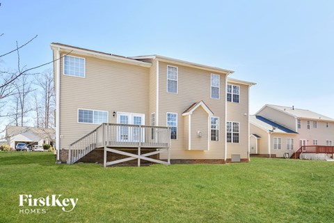 a yellow house with a deck and a grassy yard