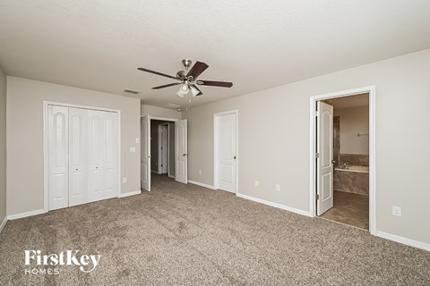a spacious living room with carpet and a ceiling fan