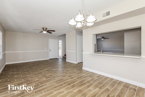 the living room and dining room with wood flooring and a ceiling fan