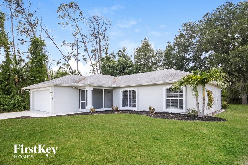 a white house with a lawn and a palm tree