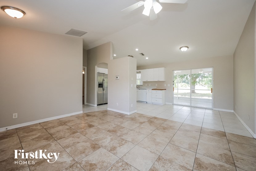 an empty living room with a kitchen in the background