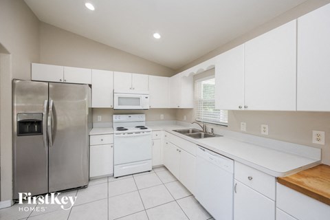 a white kitchen with white cabinets and stainless steel appliances