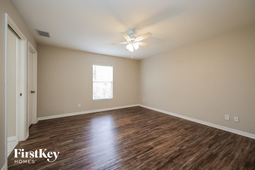 an empty living room with wood flooring and a ceiling fan