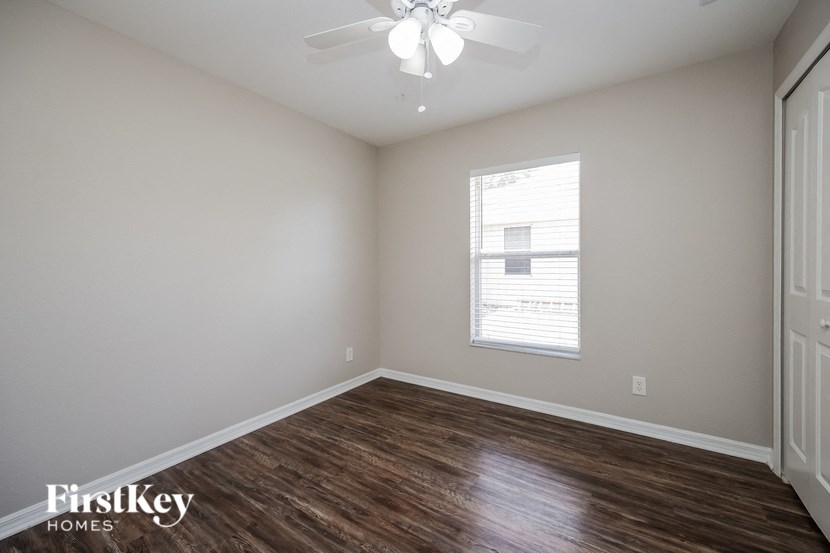 a bedroom with wood flooring and a ceiling fan