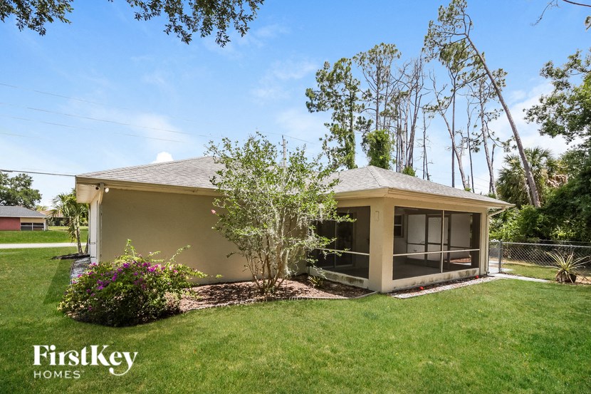a small beige house with a lawn and a tree