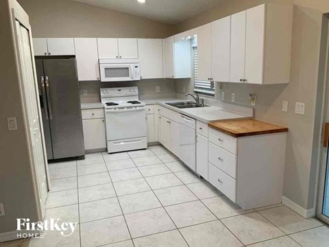 an empty kitchen with white cabinets and a white tiled floor