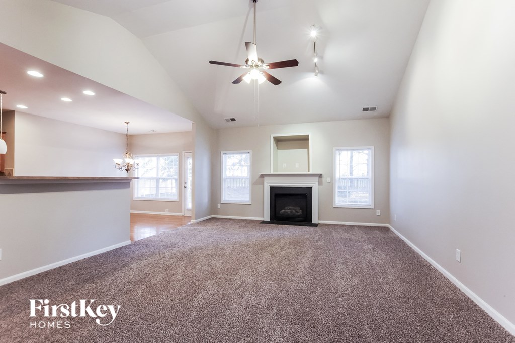 A spacious living room with a fireplace and a ceiling fan.