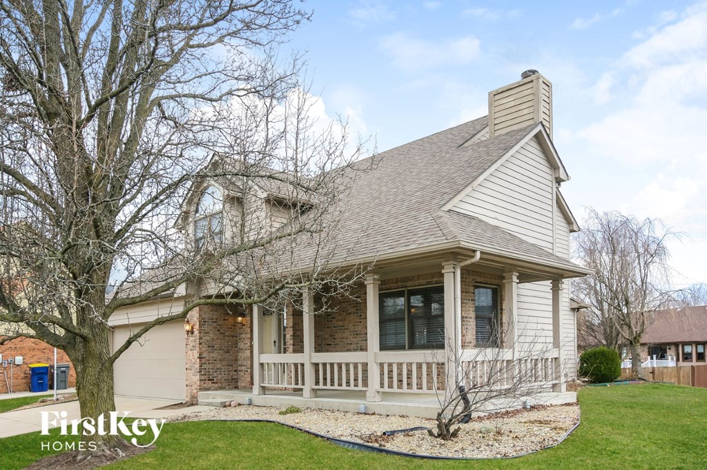 a white house with a porch and a tree