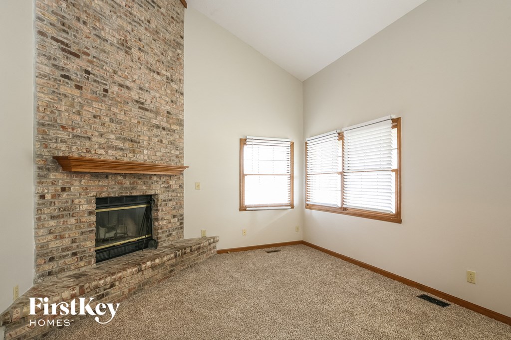a living room with a brick fireplace and two windows
