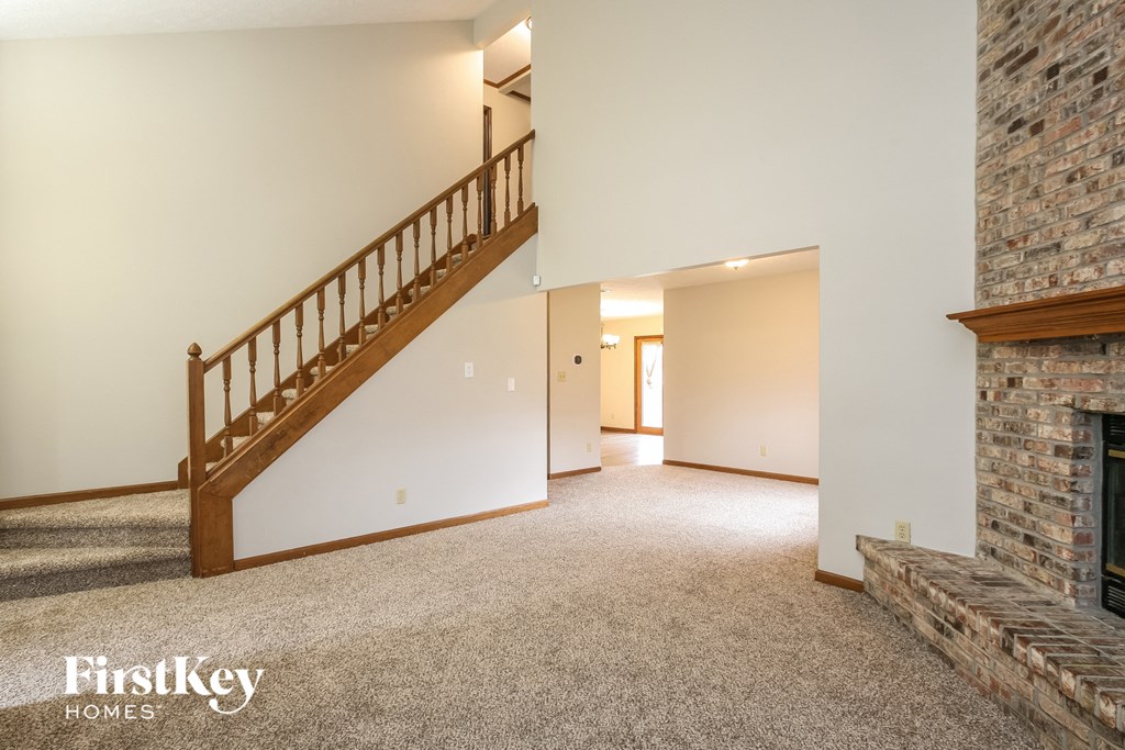 a large living room with a staircase and a fireplace
