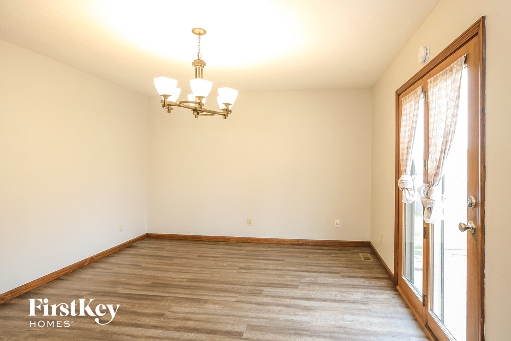 a empty living room with wood flooring and a chandelier