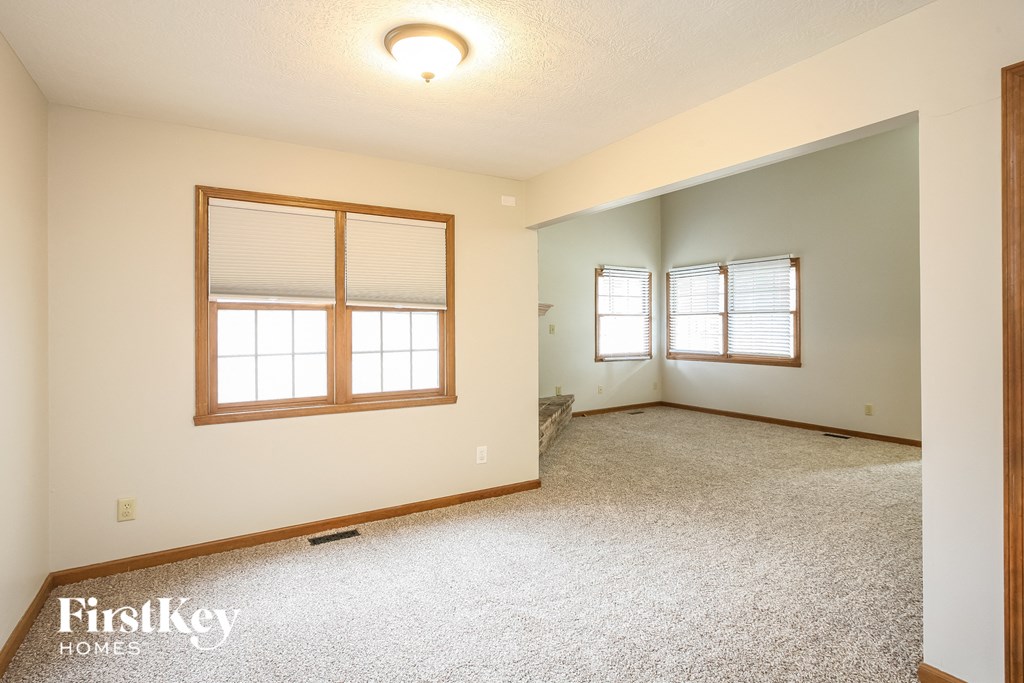 the living room of an empty house with carpet and a window