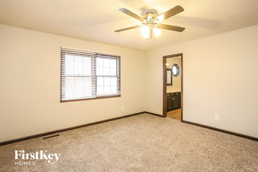 an empty living room with a ceiling fan and a window