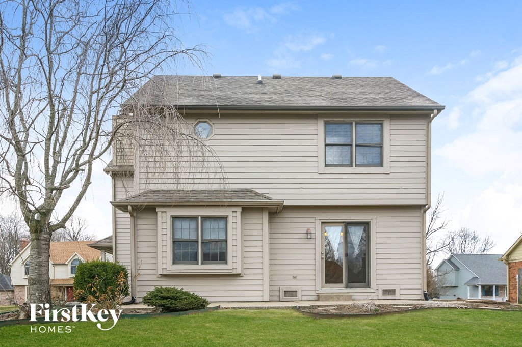the front of a house with a lawn and a tree