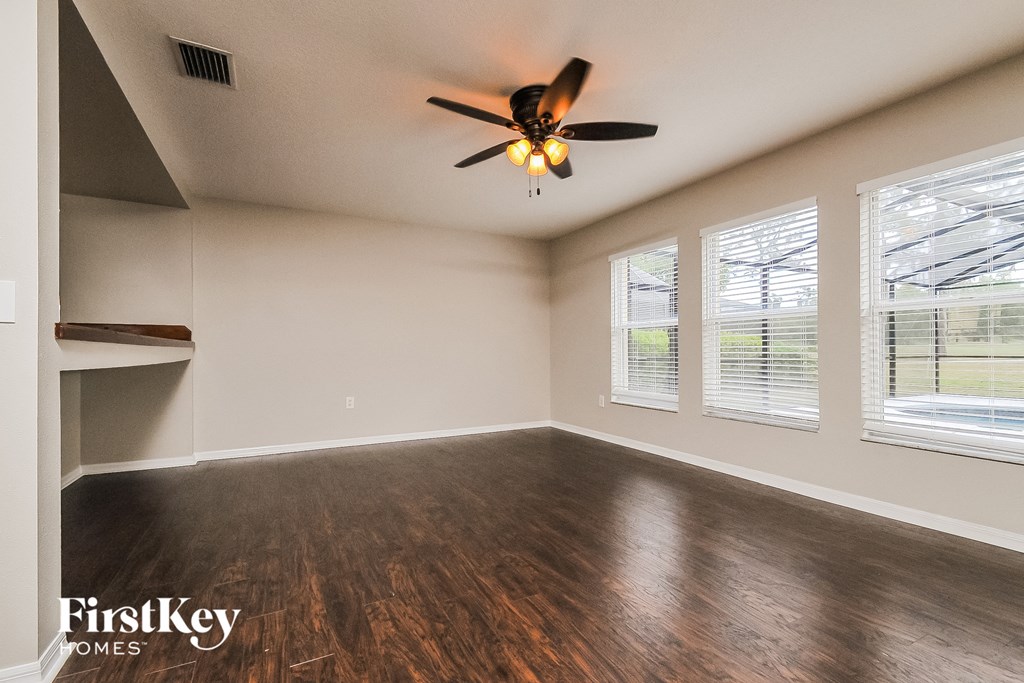 an empty living room with a ceiling fan and windows