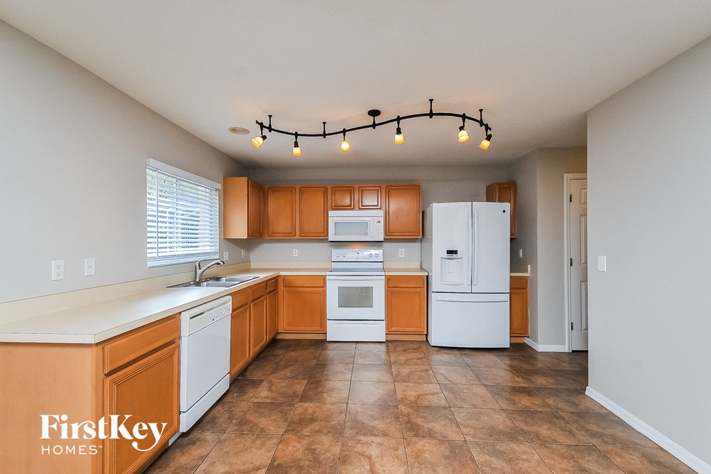 an empty kitchen with white appliances and wooden cabinets