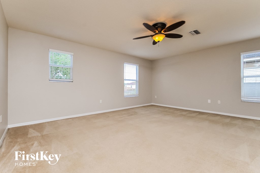an empty living room with a ceiling fan
