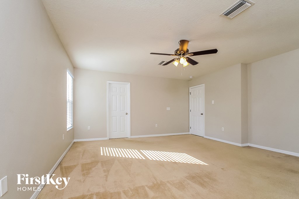 an empty living room with a ceiling fan
