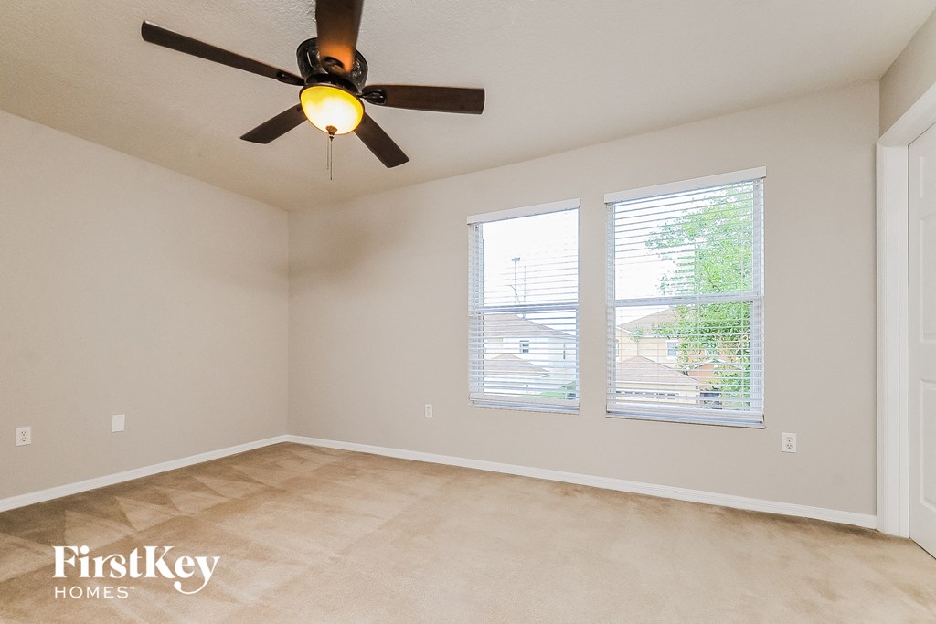 the living room of a home with a ceiling fan and two windows