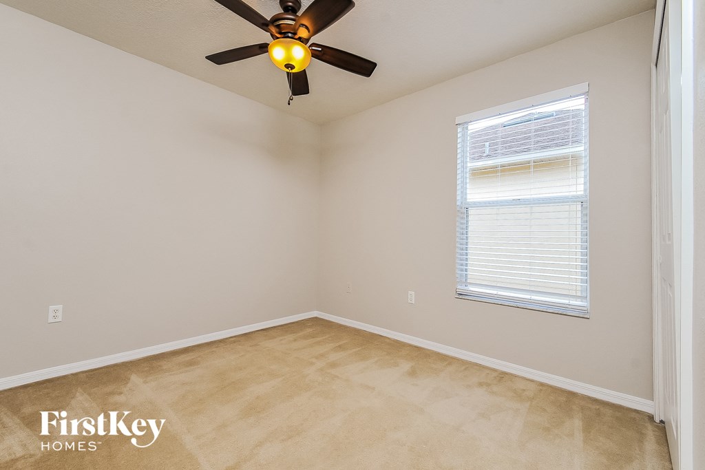 the bedroom of a home with a ceiling fan and a window