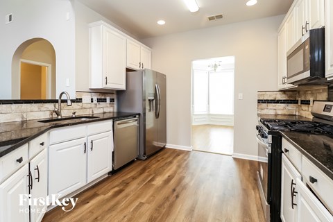 A kitchen with wooden floors and white cabinets.