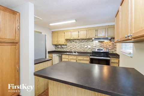 a kitchen with wooden cabinets and a black counter top