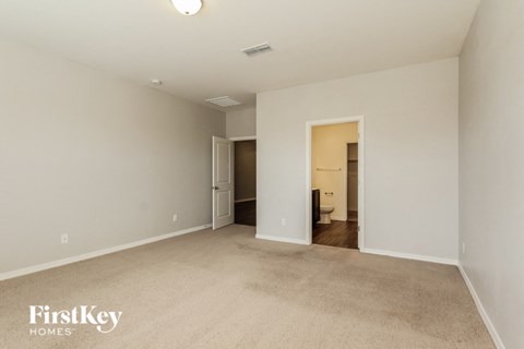 a spacious living room with carpet and a door to the bathroom
