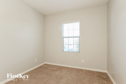 a bedroom with white walls and carpet and a window