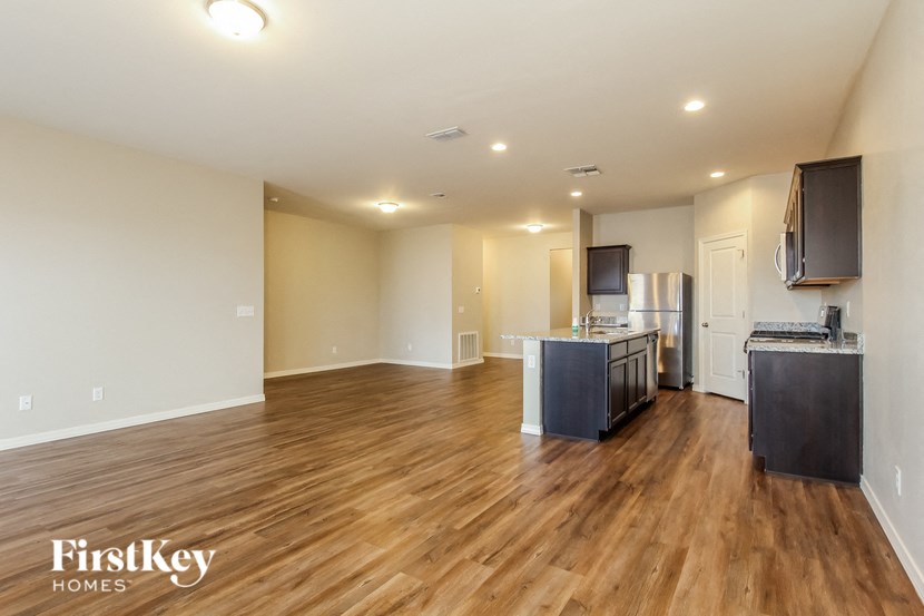 an empty living room and kitchen with wood flooring