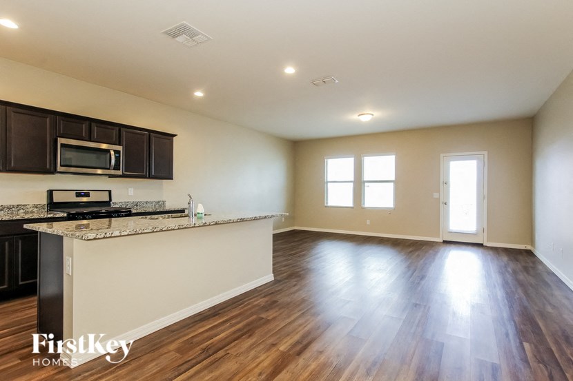 an empty living room and kitchen with wood flooring and