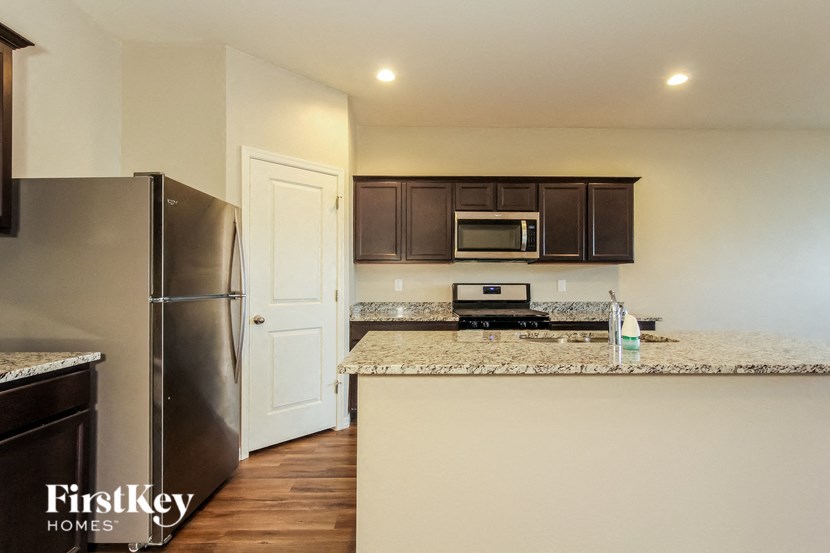 a kitchen with granite counter tops and a stainless steel refrigerator
