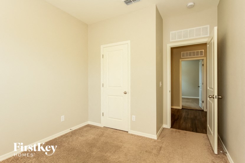 a bedroom with a white door and a hallway to a closet