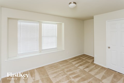 a bedroom with a window and a door and a carpeted floor