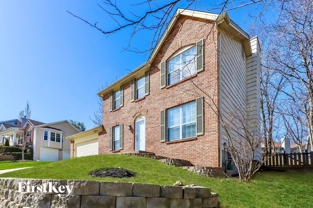 A brick house with a white garage door is for sale.