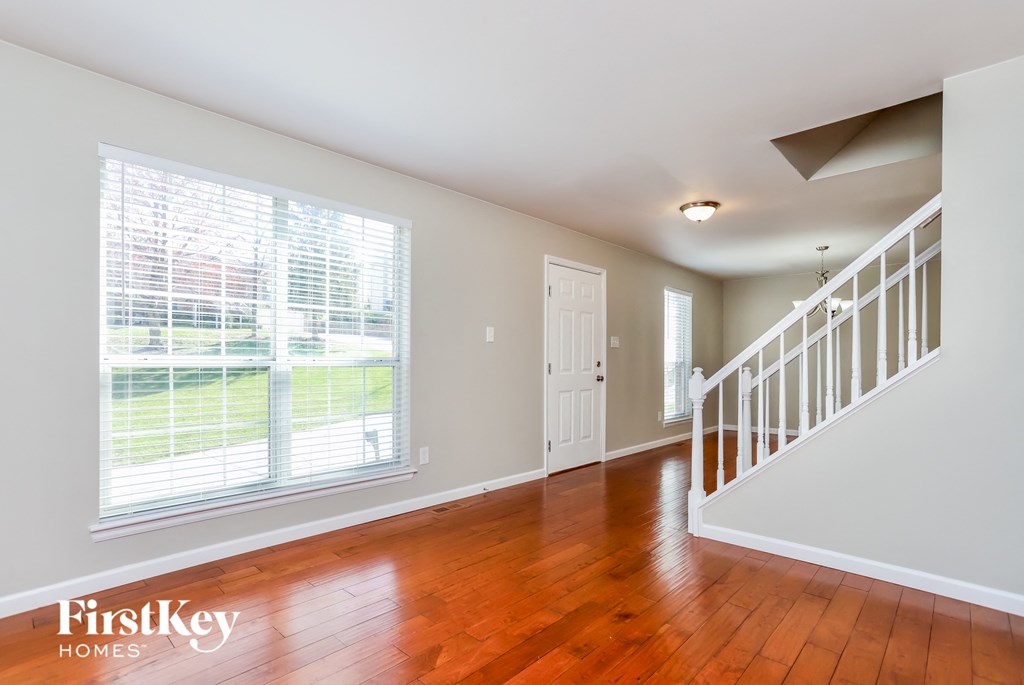 A spacious room with wooden floors and a staircase.