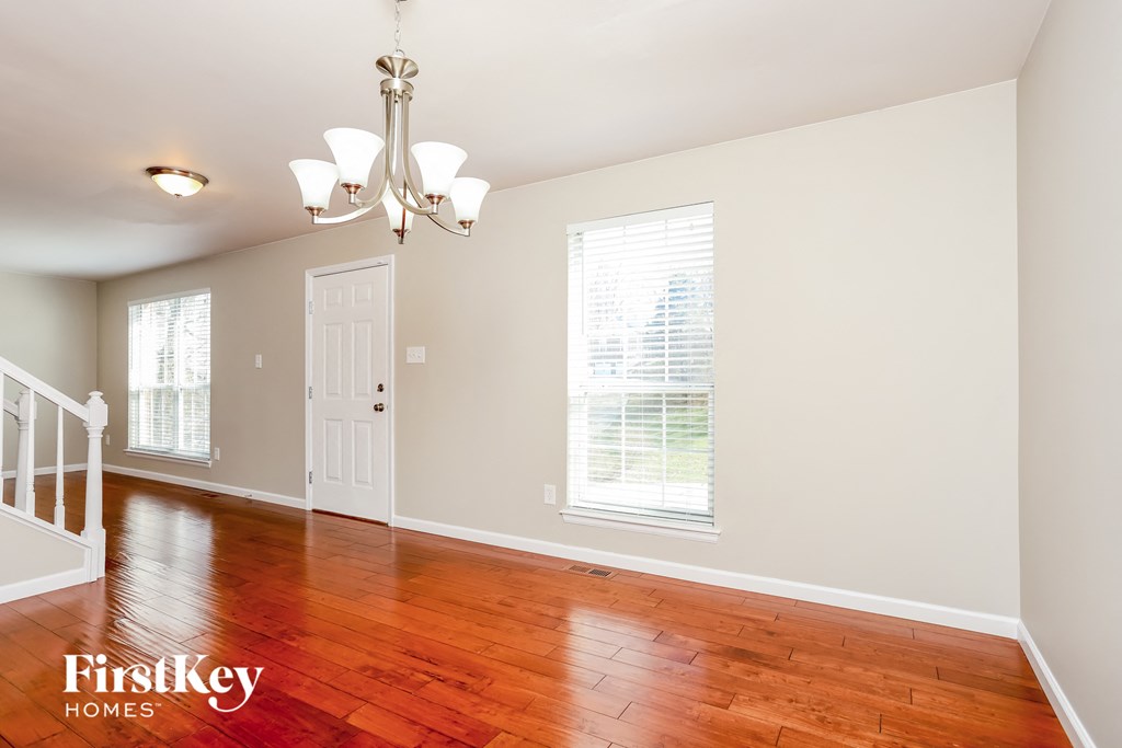 A room with a chandelier and wooden floors.