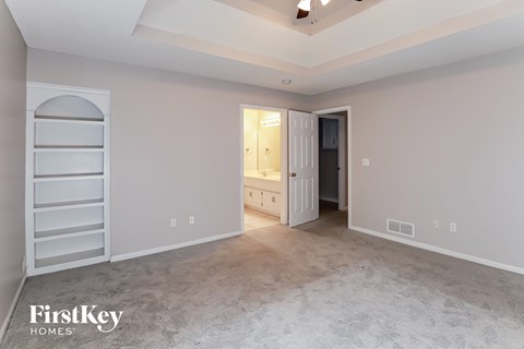 a master bedroom with a carpeted floor and a closet and a bathroom