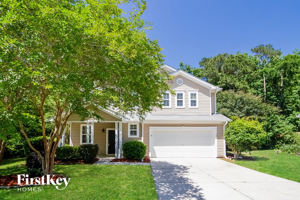 a yellow house with a white garage door and a tree