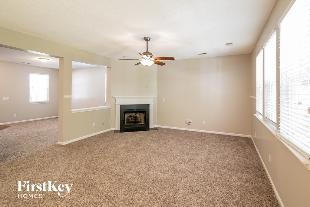 an empty living room with a fireplace and a ceiling fan