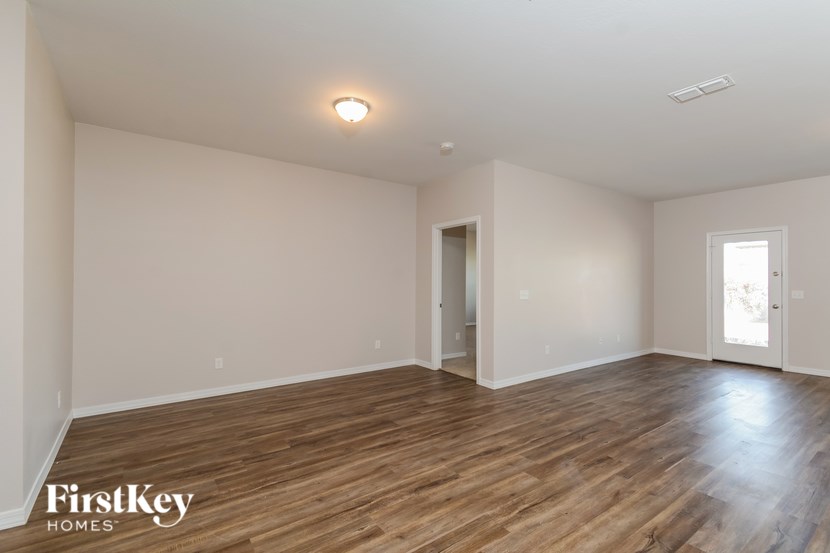A spacious room with wooden flooring and two doors.