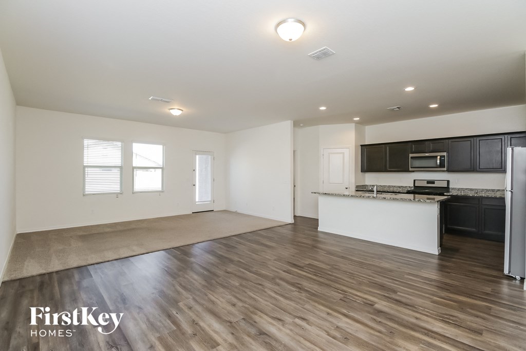 A spacious kitchen and living room with wooden floors and white walls.